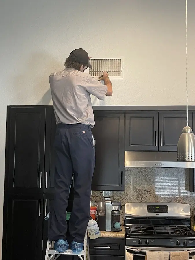 Technician inspecting an air vent during HVAC service in Onondaga